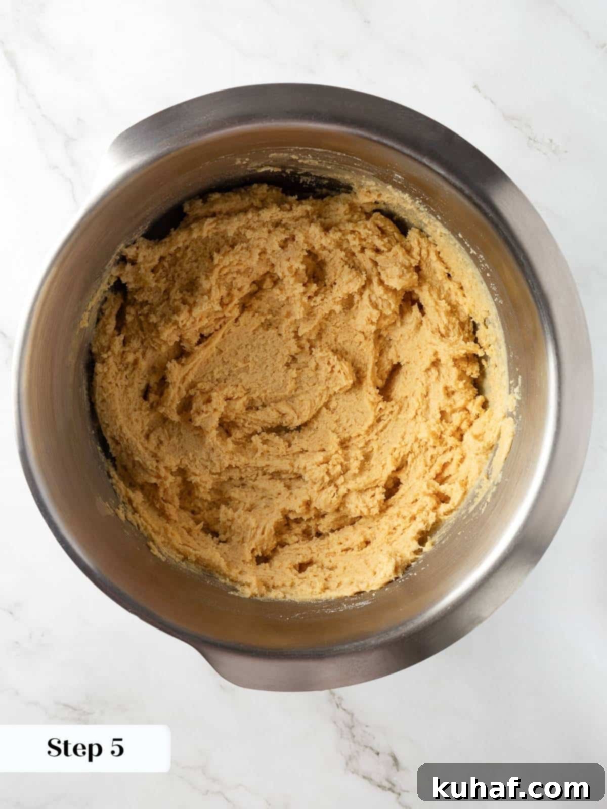 Mixing bowl showing egg and vanilla combining with creamed butter and sugar for cookies.