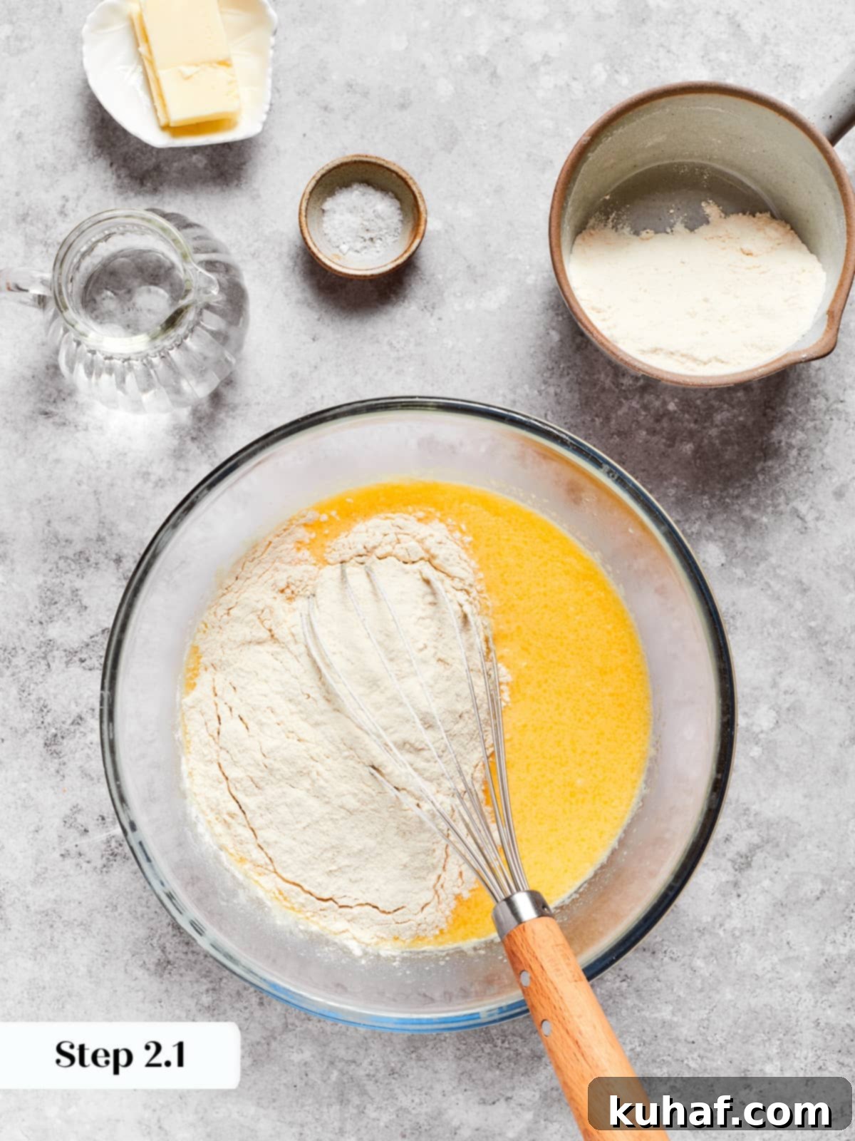Flours being whisked slowly into the wet mixture to form a smooth crepe batter.