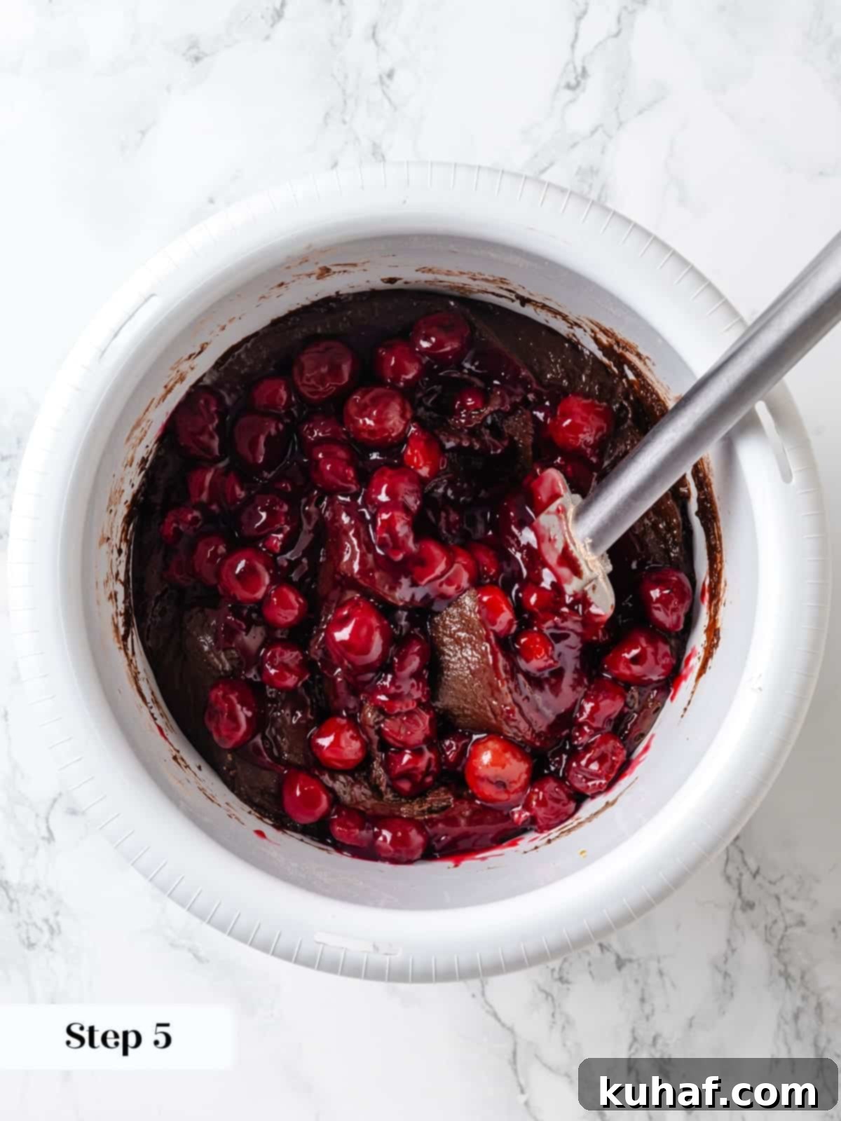 Stirring cherries into the batter to evenly distribute the fruit.