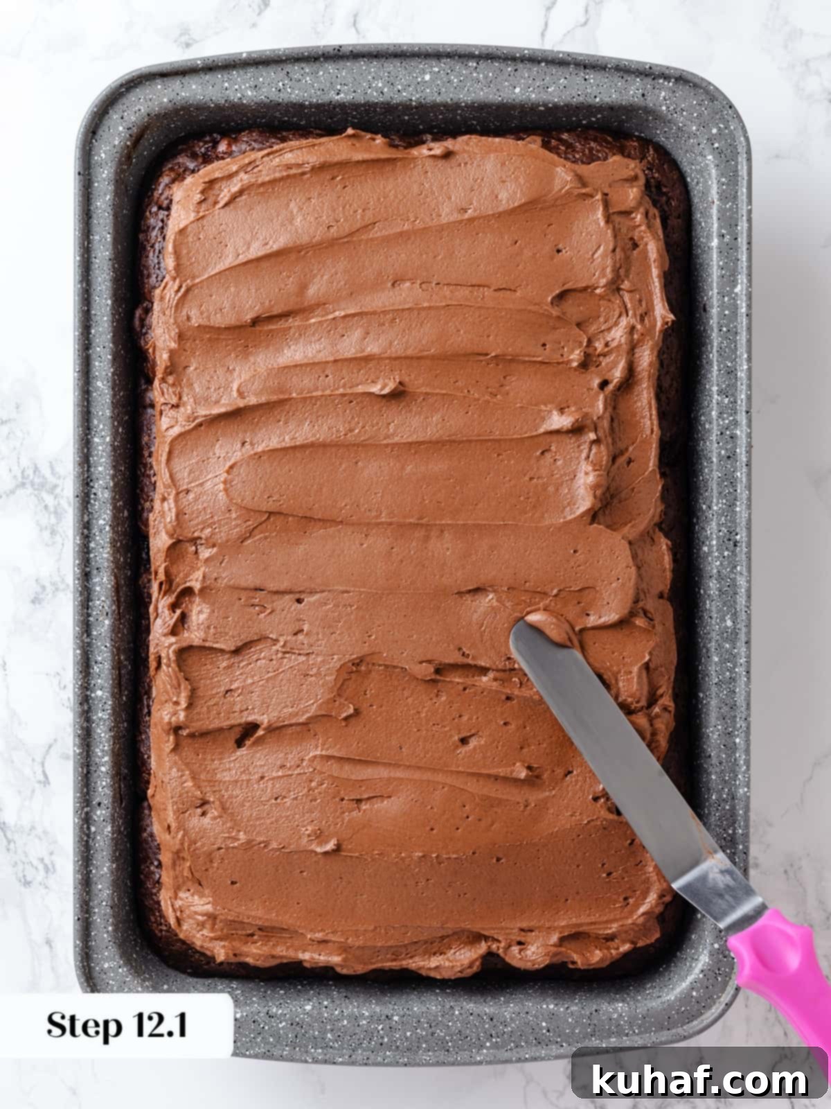 Evenly layering the frosting over the chocolate cake.