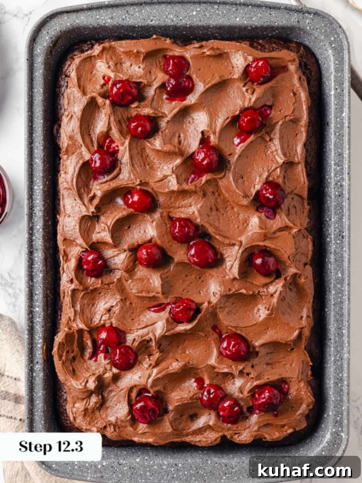 Spreading cherries gently over the chocolate cream cheese frosting on the finished cake.