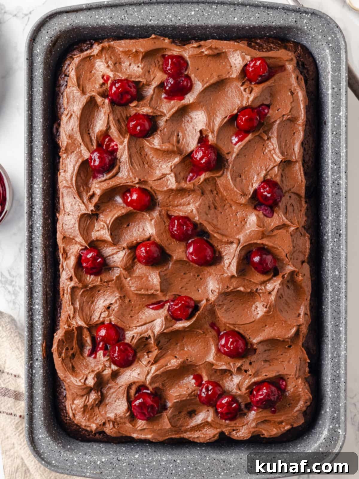 Chocolate Cream Cheese Dream Frosting 10 Uncut chocolate cake in rectangular dish topped with swirled frosting and cherries.