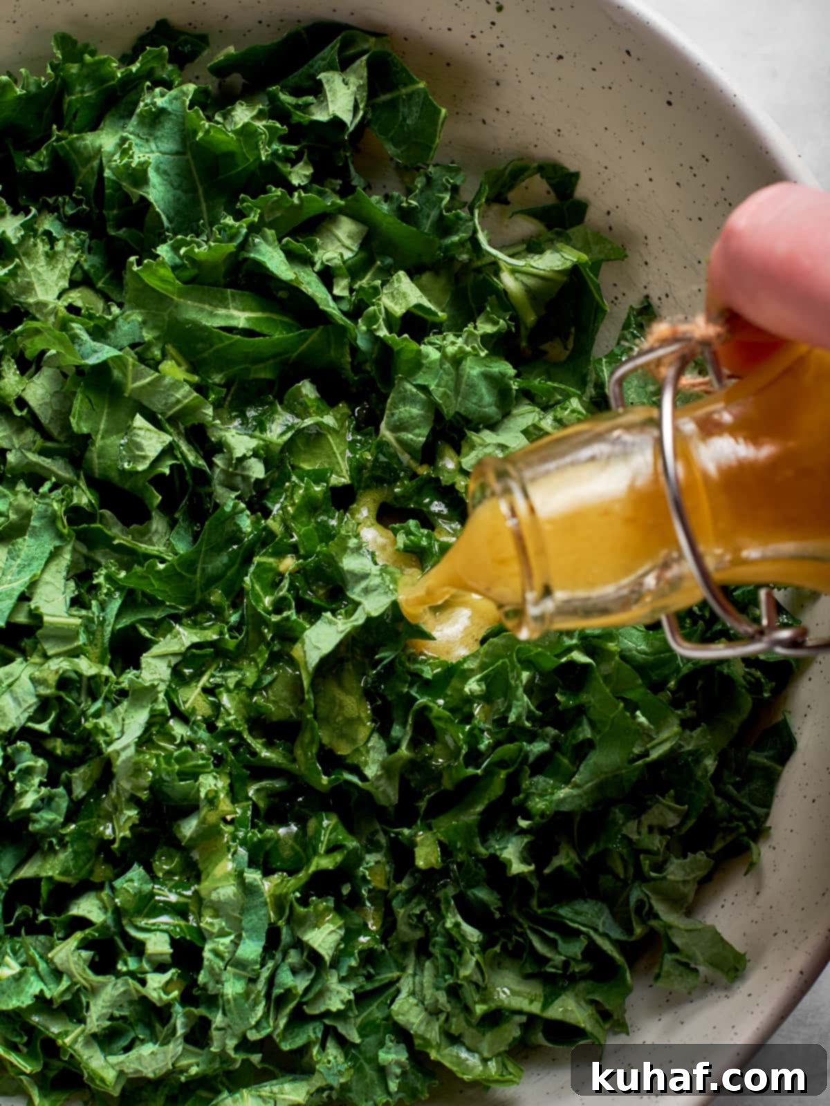Champagne vinaigrette being poured over kale salad
