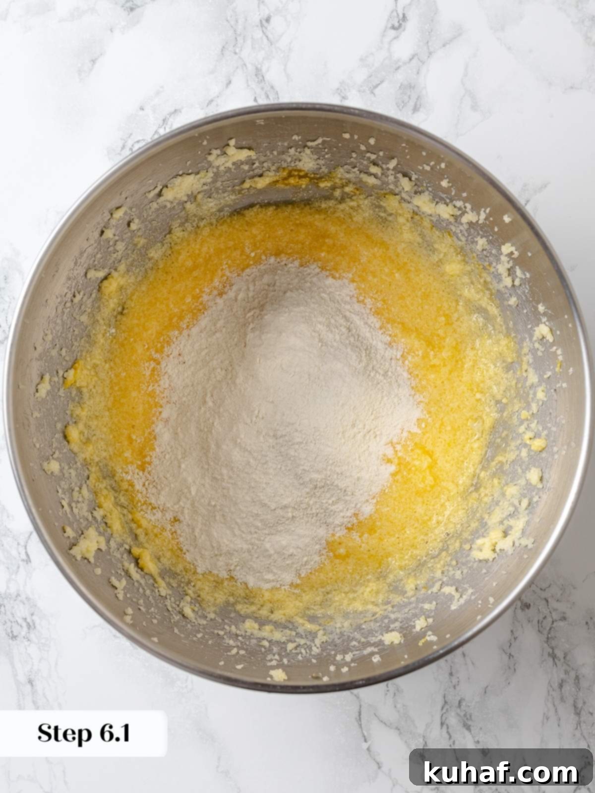 Folding flour mixture into lemon cake batter gently and evenly.