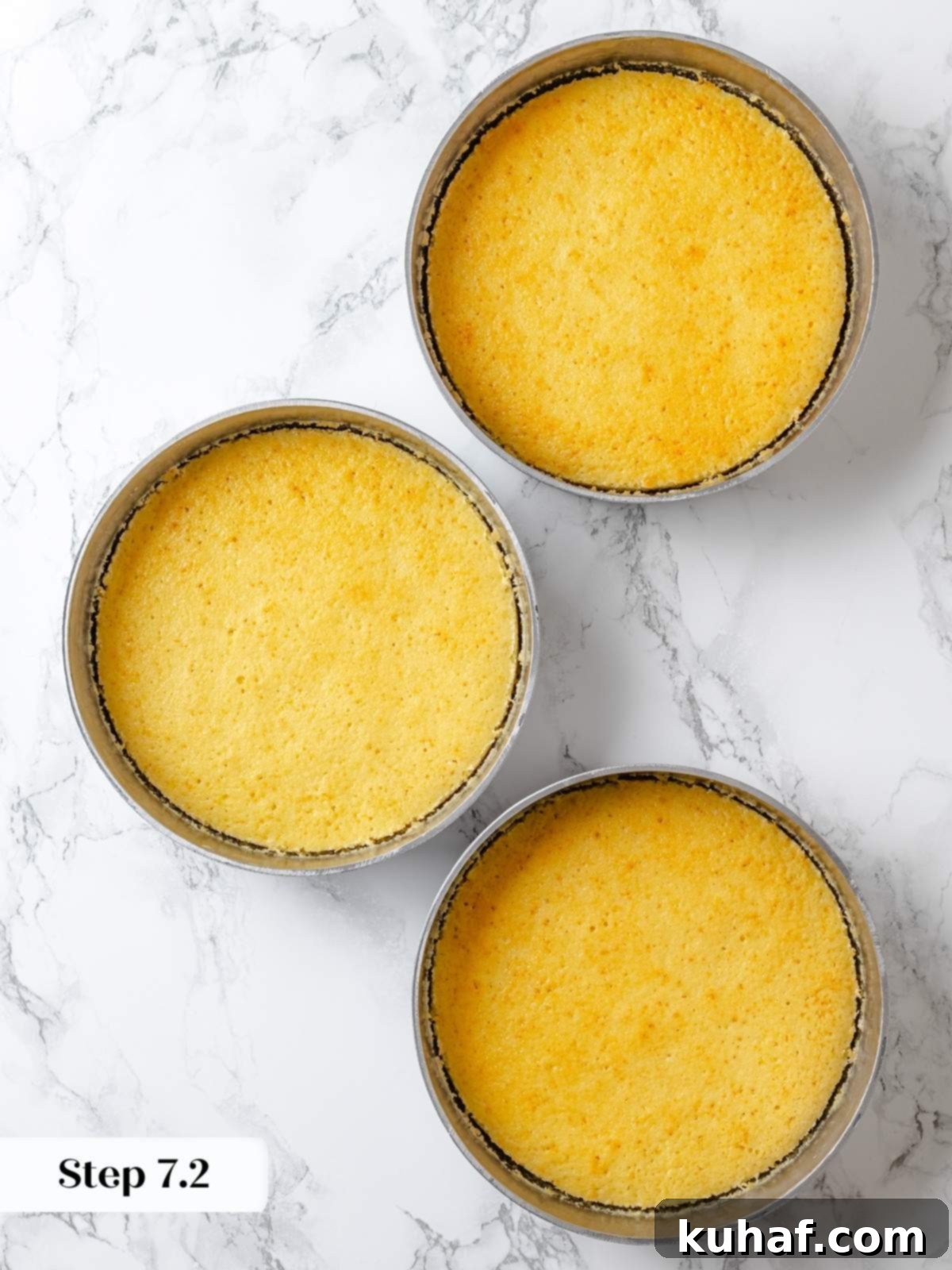 Three baked lemon cake layers cooling evenly in round cake pans.