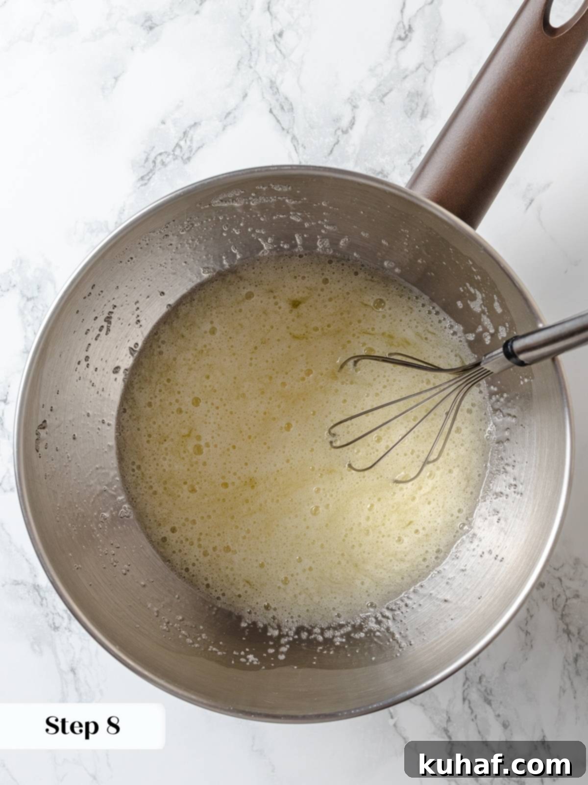 Whisking egg whites and sugar over warm water until smooth and foamy.