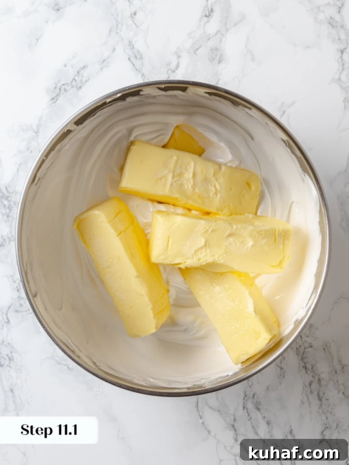 Butter being added to meringue base during buttercream mixing process.