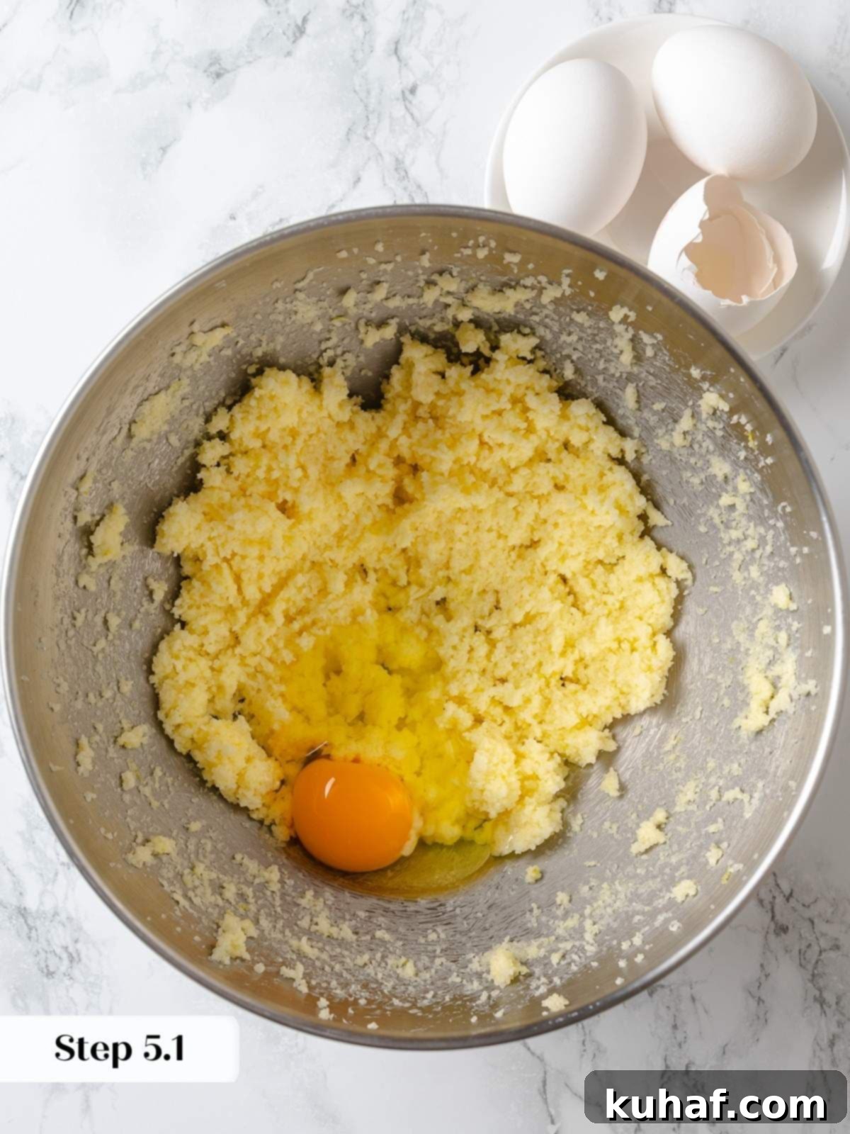 Eggs added one at a time to lemon cake batter for proper emulsification.