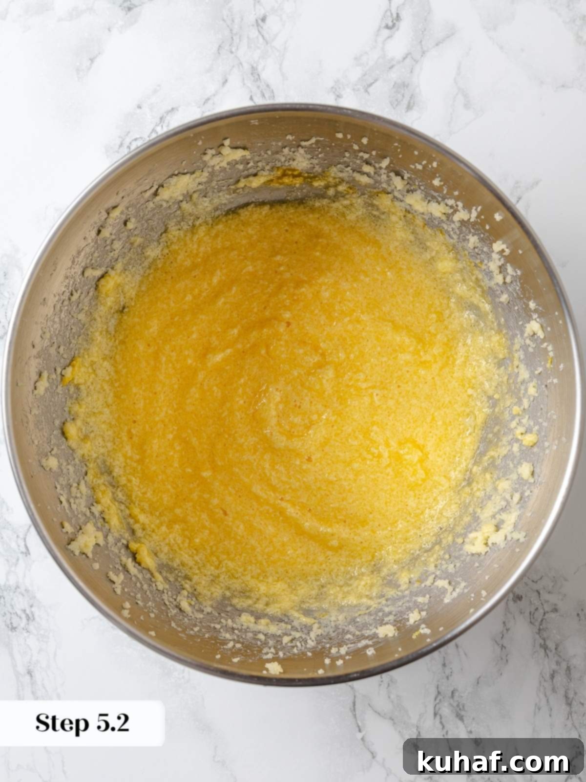 Eggs being incorporated into creamed butter and sugar for lemon cake batter.