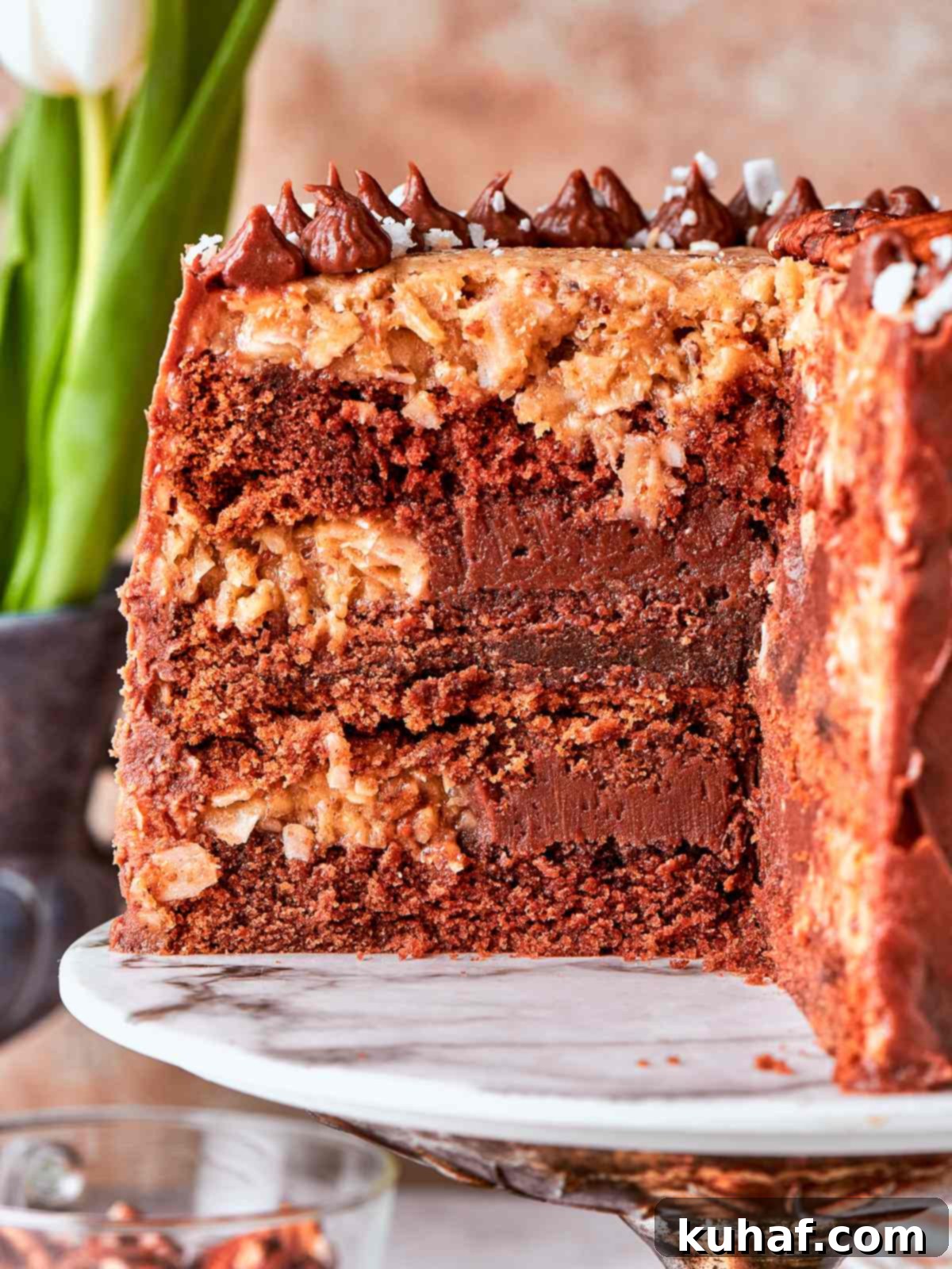 Delicious German chocolate cake on a marble cake stand, showcasing the rustic coconut pecan topping.