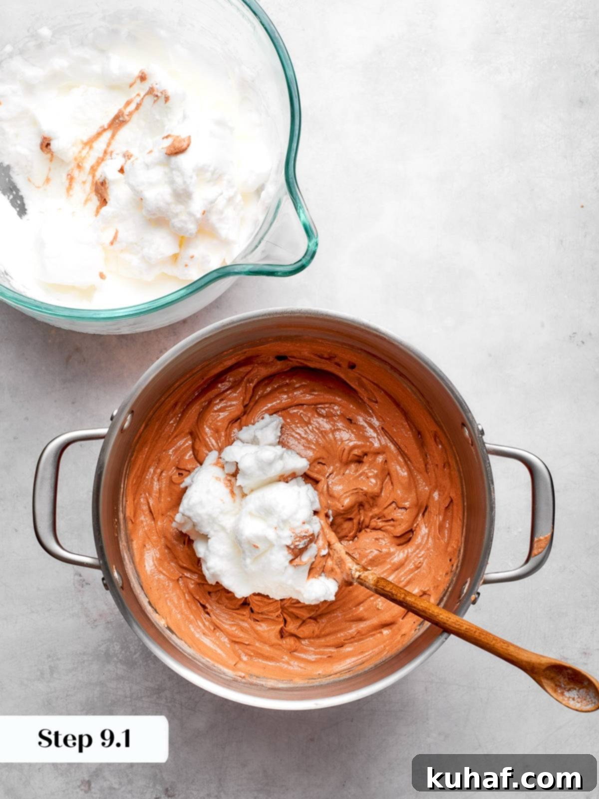 Using a spoon to gently fold stiff egg whites into the cake batter, preserving the airy mixture.