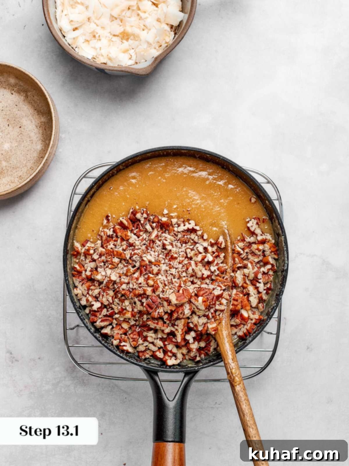 Toasted pecans being folded into the warm, caramelized coconut frosting mixture.