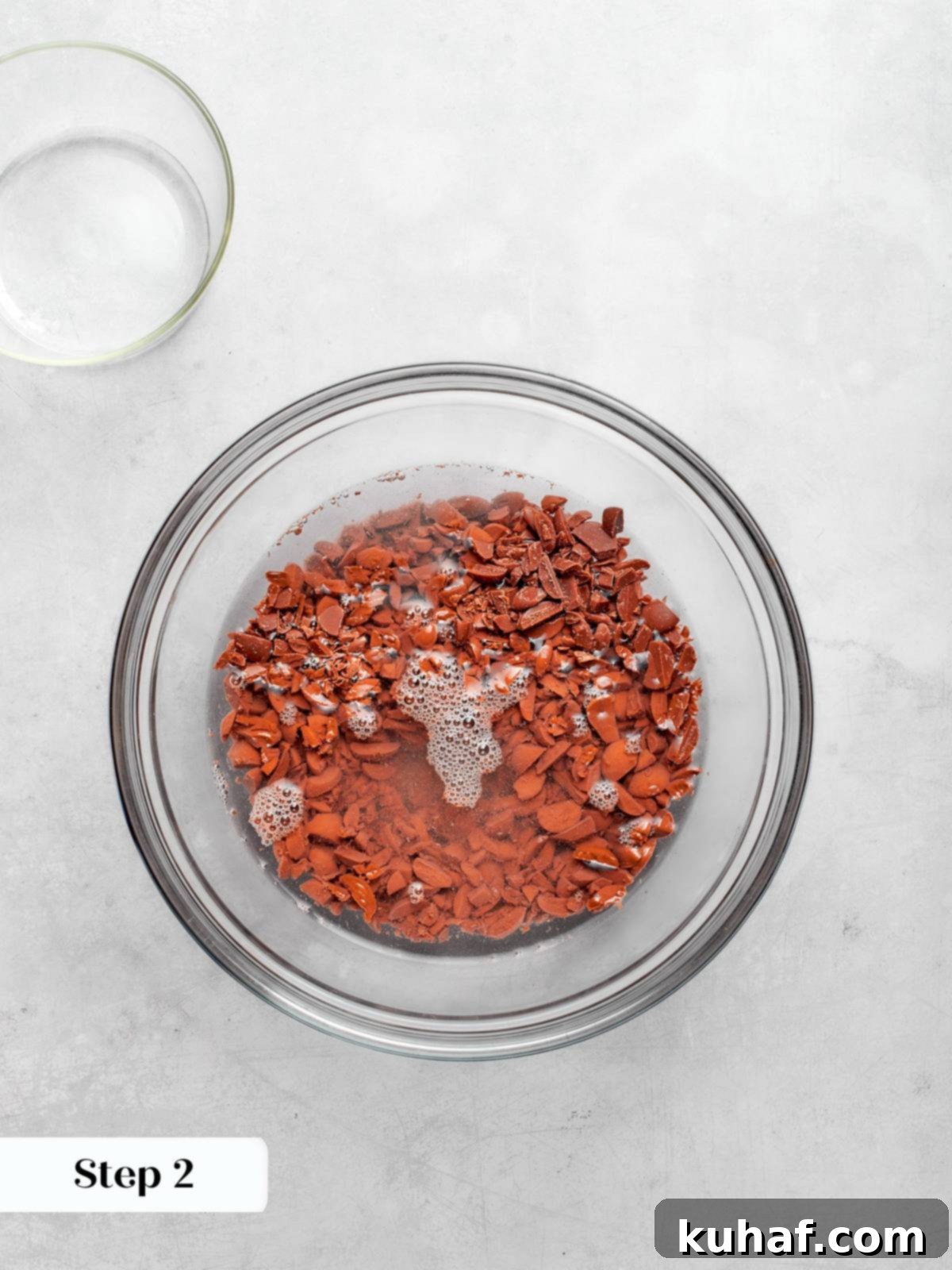 Chopped German’s chocolate melting in hot water, creating a smooth, glossy mixture.