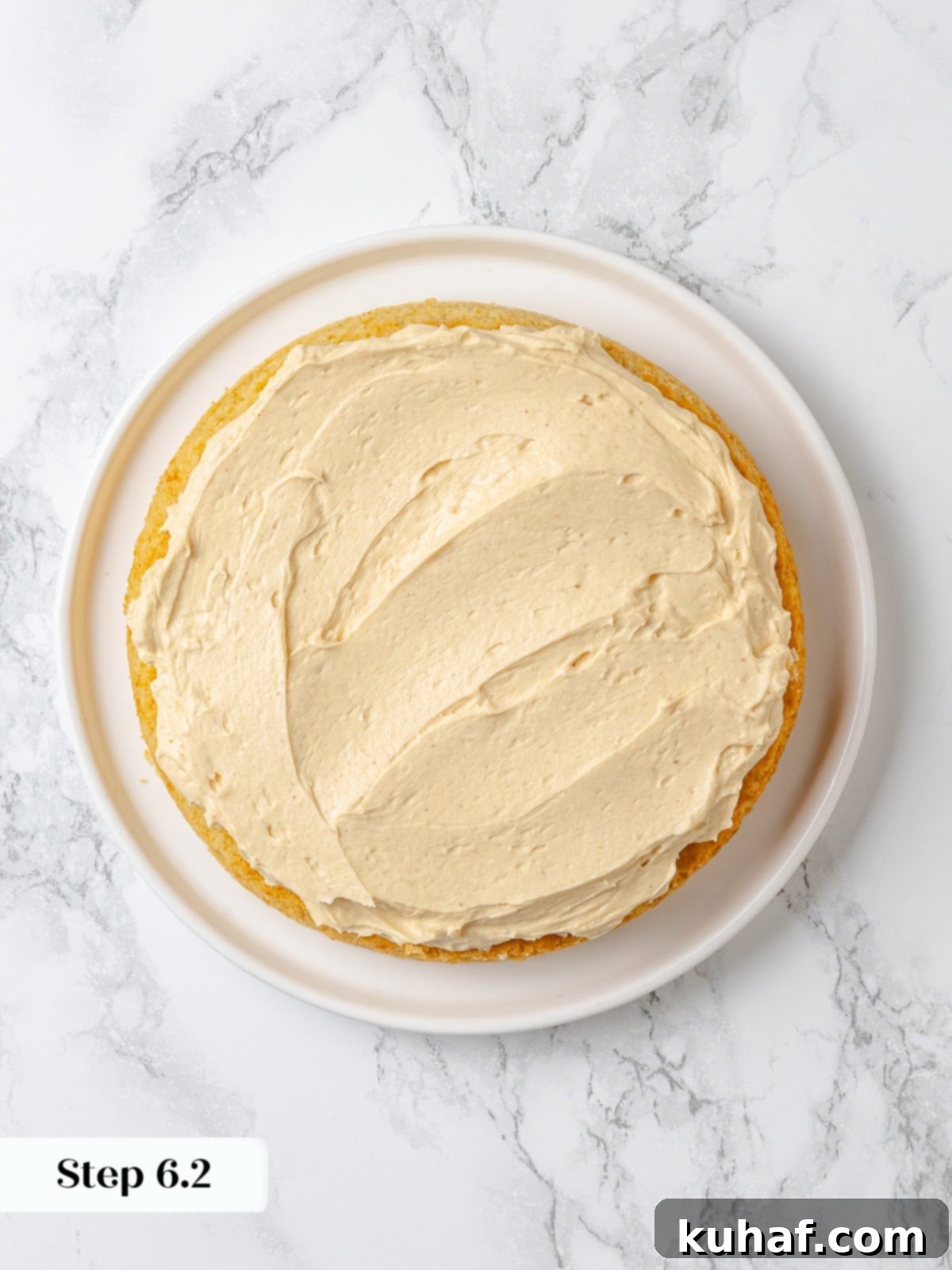 The first layer of cake covered with peanut butter buttercream before stacking the second layer.