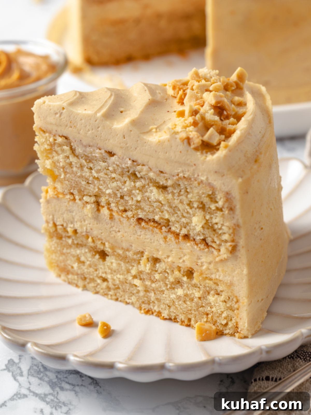 A slice of cake topped with a thick layer of fluffy peanut butter buttercream frosting.