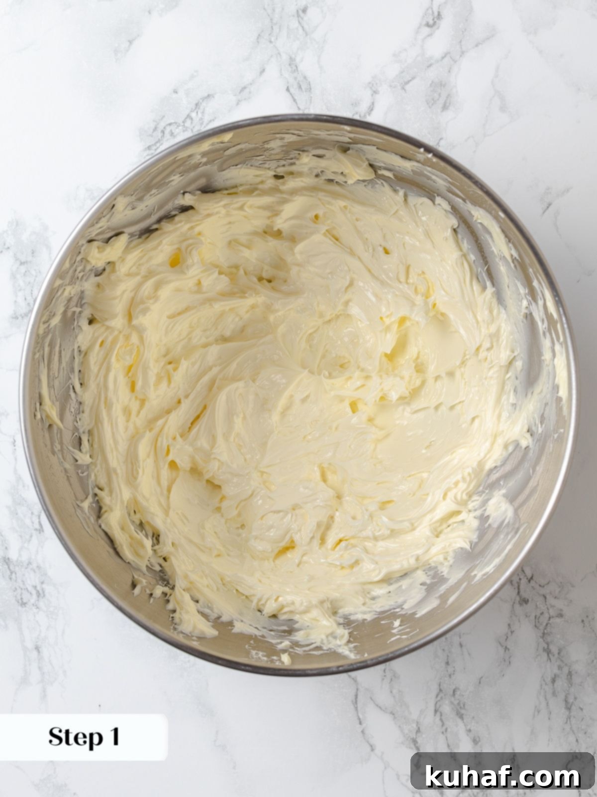 Softened butter being beaten in a stand mixer bowl, creating a fluffy base for the buttercream.