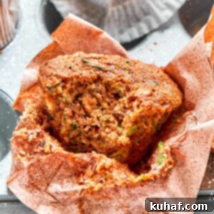 Zucchini muffin with bite taken showing moist crumb and flecks of green zucchini.