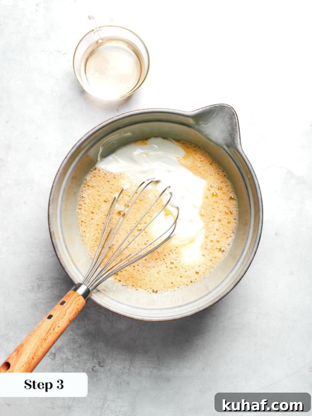 Wet ingredients including yogurt maple syrup and egg whisked together for muffin batter.