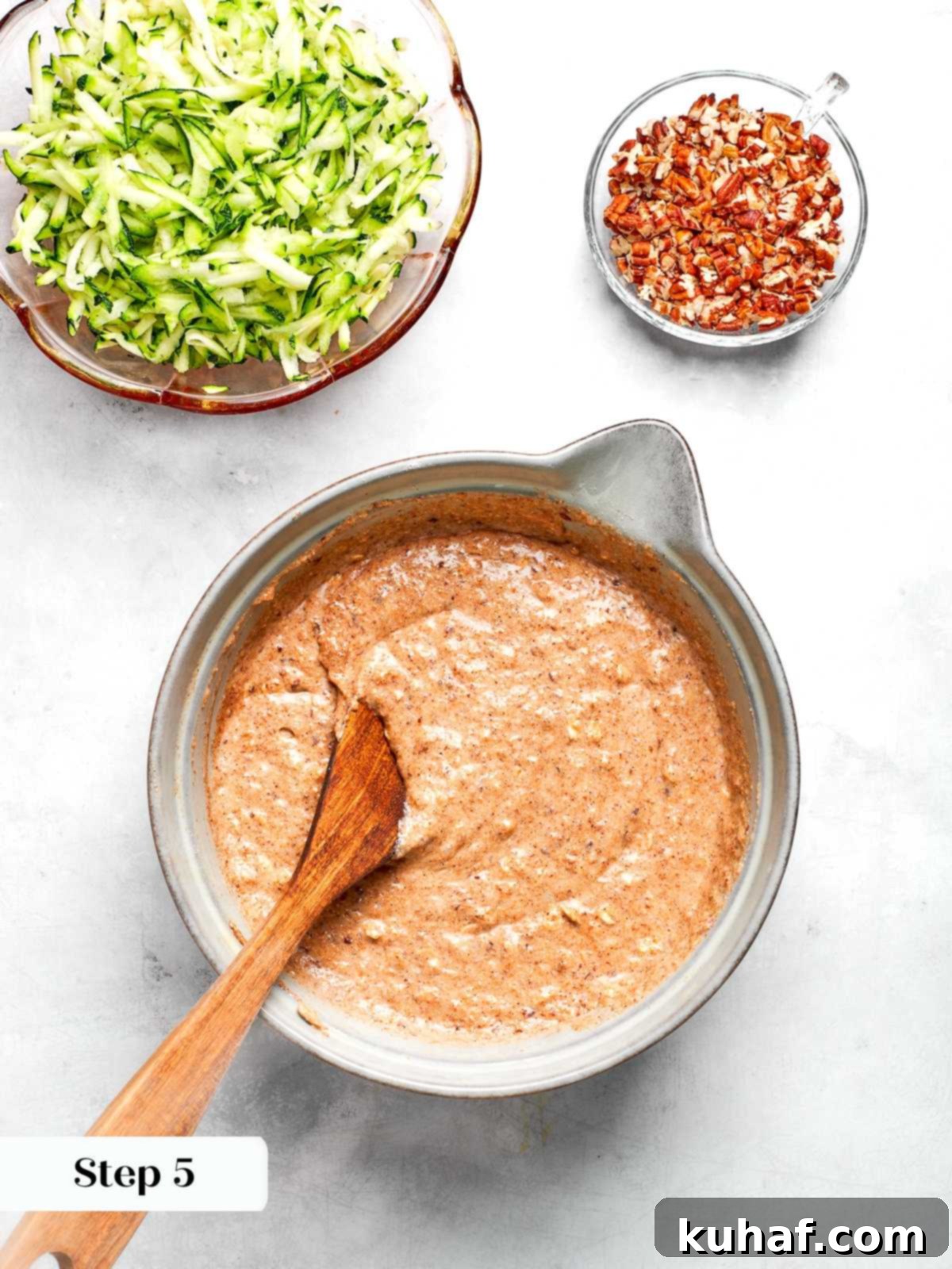 Mixing wet and dry ingredients together to form zucchini muffin batter.