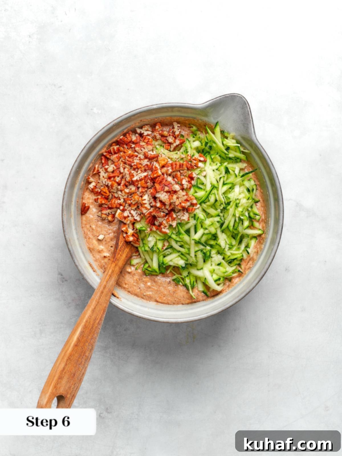 Mixing zucchini and pecans into batter for zucchini muffins.