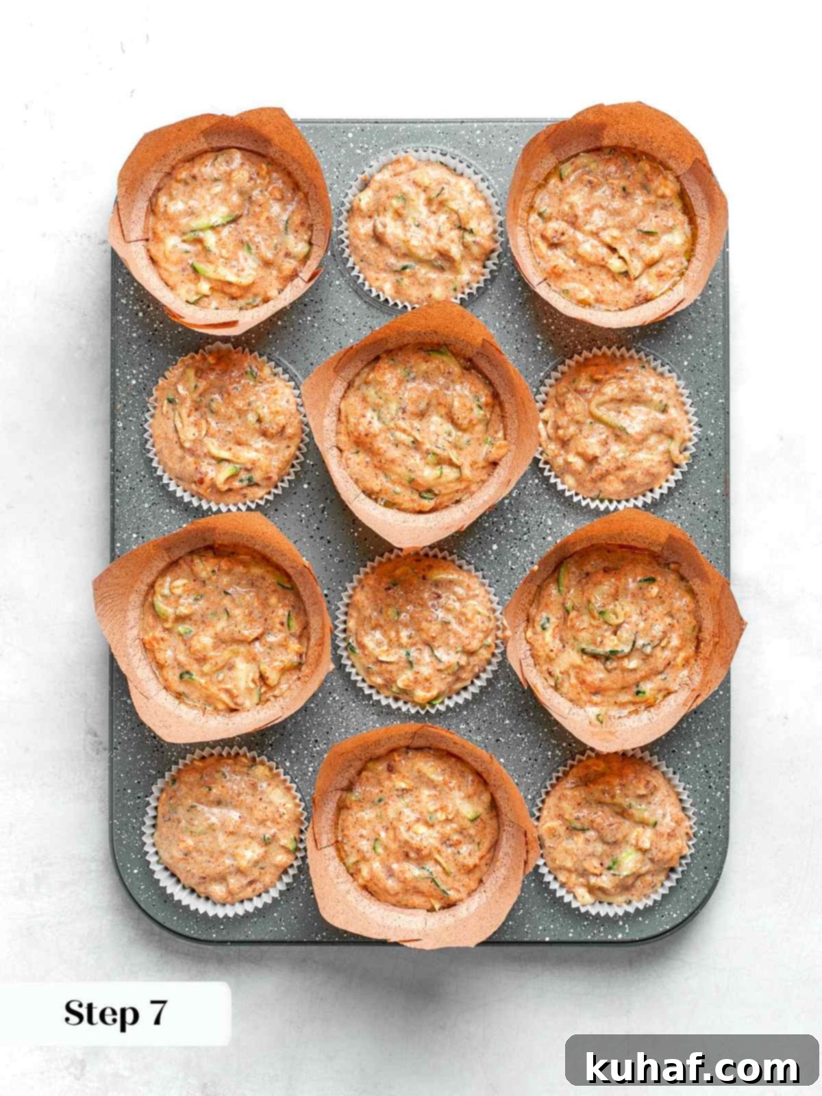 Zucchini muffin batter scooped into lined muffin cups ready for baking.